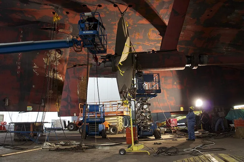 Shipyard workers preparing a ship propeller during hull antifouling regulation work