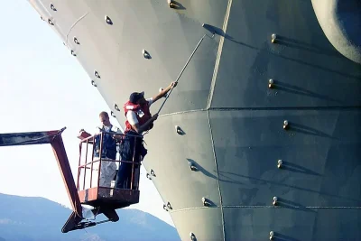Marine coating system being rolled onto a ship hull from a work platform
