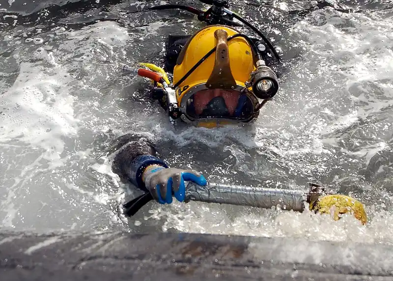 Diver scrubbing hull fouling from a vessel before new antifouling paint