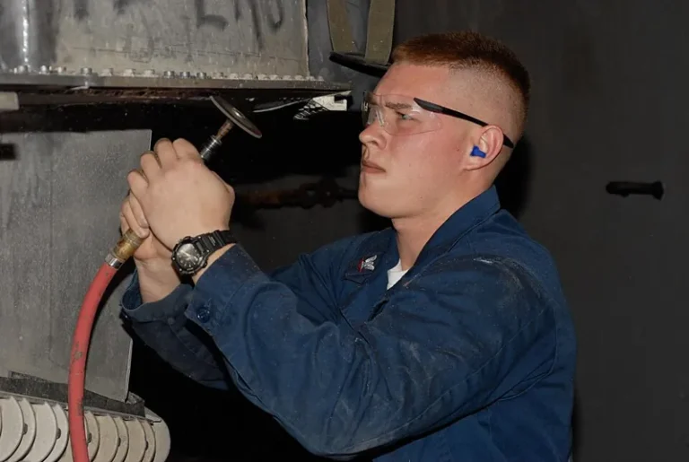 Sailor grinding corrosion from a hull, a step to prevent marine coating failures