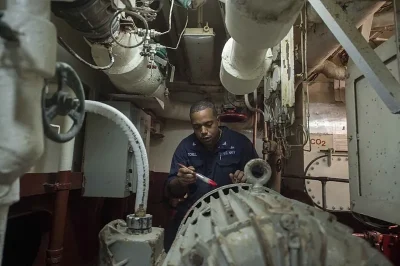 Marine coating inspection checklist: technician inspecting painted steel in a ship machinery space