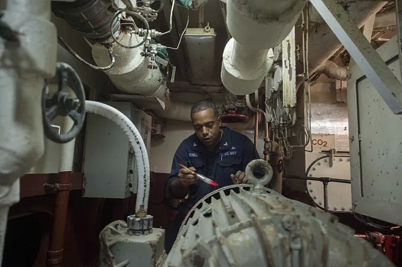 Marine coating inspection checklist: technician inspecting painted steel in a ship machinery space