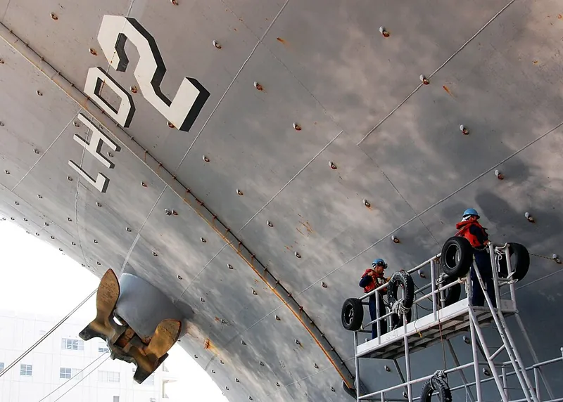 Sailors recoating a ship hull within the overcoating interval