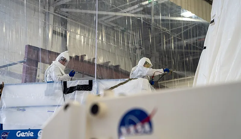 Technicians applying a protective coating to a steel surface before spark test inspection