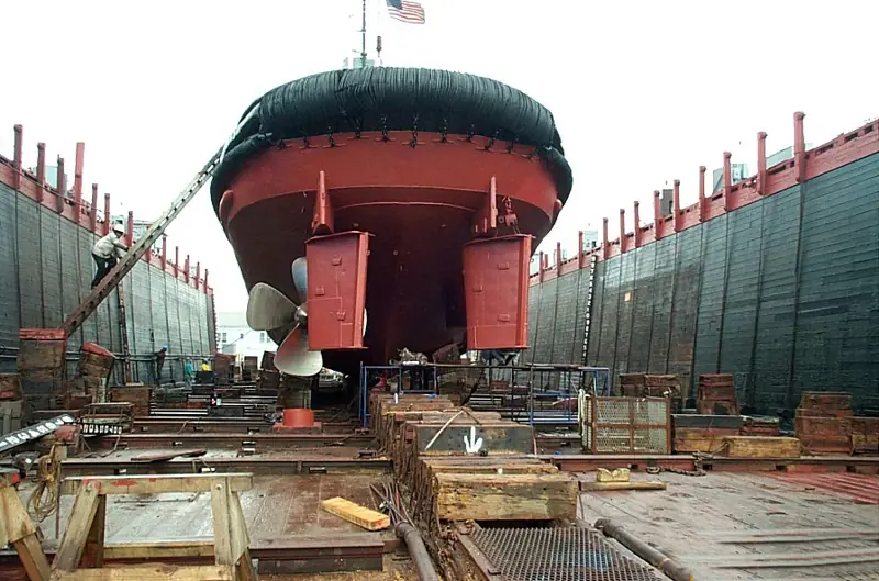 Tugboat in dry dock during hull painting with an antifouling coat